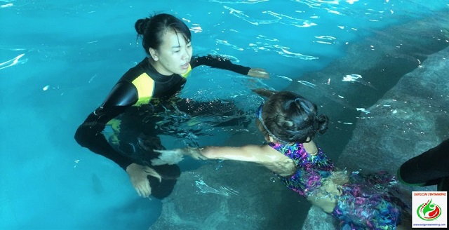 Cô giáo dạy bơi cho bé gái